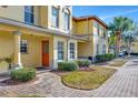 Welcoming townhouse exterior with an orange front door, and well-maintained landscaping at 3870 Island Way, St Petersburg, FL 33705