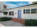 Eye-level view of the front of a white home with a bright blue front door, green bushes, and brick steps at 735 Snell Isle Ne Blvd, St Petersburg, FL 33704