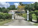 Gated entry of a home with a meticulously maintained lawn and mature landscaping offering privacy at 8946 Old Pasco Rd, Wesley Chapel, FL 33544