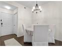 Cozy dining room featuring dark wood floors, white walls and furniture, and a round chandelier at 17106 Carrington Park Dr # 627, Tampa, FL 33647