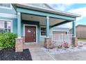 Charming covered front porch featuring decorative stone columns and a warm, inviting entrance at 10639 Carloway Hills Dr, Wimauma, FL 33598