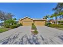 Home featuring a wide driveway leading to two-car garage, framed by lush green landscaping at 1154 Jameson Greens N Dr # 20, Sun City Center, FL 33573