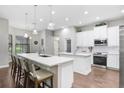 Bright kitchen with white cabinetry, large island, stainless appliances, and modern pendant lighting at 2412 Gallagher Rd, Dover, FL 33527