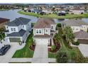 Aerial view of a home with manicured lawn, and a nearby lake at 29011 Trevi Pl, Wesley Chapel, FL 33543