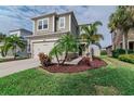 Beautiful two-story house featuring a well-manicured lawn, two car garage, and lush tropical landscaping at 29011 Trevi Pl, Wesley Chapel, FL 33543