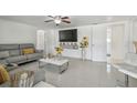 Modern living room featuring a gray sectional sofa, white tile floors, and ample natural light at 8025 N Gomez Ave, Tampa, FL 33614