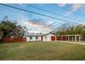 Charming single-story home featuring a wooden fence, covered parking, and a manicured lawn under a cloudy sky at 208 Palmetto W Rd, Nokomis, FL 34275