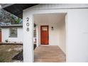Inviting front porch with a modern wood-look tile floor and a stylish wooden front door with glass inserts at 208 Palmetto W Rd, Nokomis, FL 34275