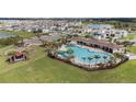 Aerial view of community pool, playground, lush lawns, and water views at 5640 Wandering Willow Dr, Wesley Chapel, FL 33545