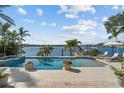 A beautiful waterfront pool with a serene view of the bay, palm trees, and inviting lounge chairs at 1100 Cordova Ne Blvd, St Petersburg, FL 33704