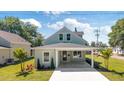Inviting two-story home featuring lush landscaping, a quaint covered porch, and a freshly paved walkway at 25 W Edwards St, Plant City, FL 33563