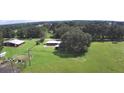 Aerial view featuring a barn, shed, and fenced grounds with lush greenery at 32817 Leonard Rd, San Antonio, FL 33576