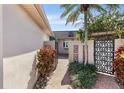 Inviting courtyard entrance featuring decorative iron gates, lush plants, and a patterned brick walkway at 672 Boca Ciega Point N Blvd, St Petersburg, FL 33708