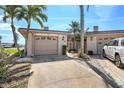 Charming exterior showcasing the home's two-car garage, complemented by lush landscaping and mature palm trees at 672 Boca Ciega Point N Blvd, St Petersburg, FL 33708