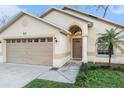 Welcoming home featuring an attached garage, a charming front entrance, and fresh landscaping at 918 W Knollwood St, Tampa, FL 33604