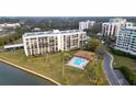 Striking exterior view featuring manicured lawn, community pool, and multi-story condominium building at 100 Oakmont Ln # 605, Belleair, FL 33756