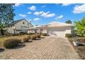 Pretty front exterior of home, showcasing the white tiled roof, brick driveway, and mature landscaping at 10427 Spoonbill W Rd, Bradenton, FL 34209