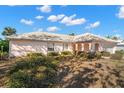 View of the exterior showing the white-tile roof, landscaping and arched entry to this lovely, light pink house at 10427 Spoonbill W Rd, Bradenton, FL 34209