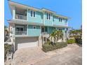 Coastal home with a striking blue exterior, white trim, a balcony, and convenient garage access at 30 79Th Ave, Treasure Island, FL 33706