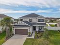 Areal view of a charming two-story home with well-manicured lawn, a two-car garage, and beautiful landscaping at 34159 Astoria Cir, Wesley Chapel, FL 33545