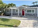 Stylish single-Gathering home with a red door, a stone facade, a paver driveway and decorative pergola at 3419 W Empedrado St, Tampa, FL 33629