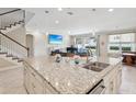 Open kitchen featuring a granite island and bar with pendant lighting, seamlessly flowing into the living space at 3667 Arbor Chase Dr, Palm Harbor, FL 34683