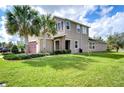 Beautiful two-story home on a large lot featuring lush green grass and mature palm trees at 4627 Tramanto Ln, Wesley Chapel, FL 33543