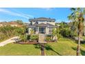 Elegant home features a grand entrance with a staircase, well-manicured lawn, and lush tropical landscaping at 4707 Troydale Rd, Tampa, FL 33615