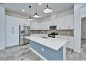 Bright kitchen features stainless steel appliances and a blue center island with pendant lighting at 729 Winterside Dr, Apollo Beach, FL 33572