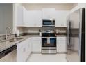 Bright kitchen with stainless steel appliances, white cabinets, and granite countertops at 11903 Castine St, New Port Richey, FL 34654