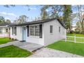 Charming home featuring a light blue front door, a white picket fence and freshly cut lawn at 1503 W Hamilton Ave, Tampa, FL 33604