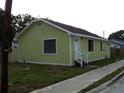 Quaint one-story home with a welcoming white front door, set against a cloudy sky and a sidewalk at 1554 Tilley Ave, Clearwater, FL 33756