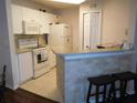 Bright kitchen with white cabinets and appliances, featuring a breakfast bar with seating and tiled floor at 18106 Peregrines Perch Pl # 5208, Lutz, FL 33558