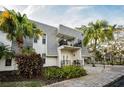 Exterior view of the condo featuring a balcony, palm trees, and well-maintained landscaping at 700 Lyndhurst St # 1024, Dunedin, FL 34698