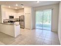 Modern kitchen featuring white cabinets, stainless steel appliances, and sliding glass doors to patio at 11115 Wishing Cloud Rd, Land O Lakes, FL 34638