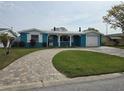 Charming blue home with a well-manicured lawn, brick driveway, and a one car garage at 12734 2Nd Isle, Hudson, FL 34667