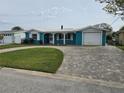 Charming blue home with a well-manicured lawn, brick driveway, and a one car garage at 12734 2Nd Isle, Hudson, FL 34667