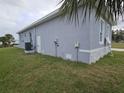 Side view of gray stucco home with well-maintained lawn and utilities at 14300 Kay Ln, Port Charlotte, FL 33981