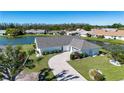 Stunning aerial view of a single-story home with a brick driveway, lush lawn, and beautiful lake view at 1742 W Del Webb Blvd, Sun City Center, FL 33573