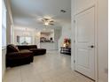 Bright living room features tile floors, a comfortable brown sofa, ceiling fan, and open layout at 17567 Nectar Flume Dr, Land O Lakes, FL 34638