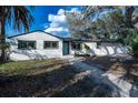 Charming one-story home with a blue front door, black-framed windows, and a brick pathway at 2102 E Hamilton Ave, Tampa, FL 33610