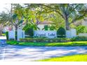 Community entrance sign with lush landscaping featuring beautiful plants and manicured green shrubbery at 3367 Crystal E Ct # F, Palm Harbor, FL 34685