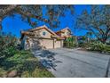 Exterior view of a two-car garage and private driveway leading to a home with a red tile roof at 4677 Aylesford Dr, Palm Harbor, FL 34685