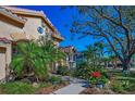 Close exterior showcasing colorful landscaping, a walkway, and partial view of the home's architectural details and front yard at 4677 Aylesford Dr, Palm Harbor, FL 34685
