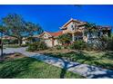 A beautiful single-Gathering home showing the manicured front yard and mature shade trees on a sunny day at 4677 Aylesford Dr, Palm Harbor, FL 34685