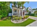 Charming home featuring a small porch, a manicured garden and a well-kept lawn with several palm trees at 47 Adalia Ave, Tampa, FL 33606