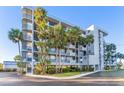 Beautiful condo building featuring multiple stories, balconies, and mature palm trees enhancing curb appeal at 4823 Ebbtide Ln # 303, Port Richey, FL 34668