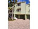 Charming two-story townhouse featuring a private garage and a welcoming entrance with white Adirondack chairs at 530 Sandy Hook Rd, Treasure Island, FL 33706