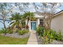 Inviting front entrance boasting a blue door, lush landscaping, and a stone walkway at 7308 Carrington Oaks Ln, Apollo Beach, FL 33572