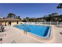 Community pool with crystal clear water, ample lounge chairs, fenced perimeter and nearby pool house at 8158 Eagles Park N Dr, St Petersburg, FL 33709